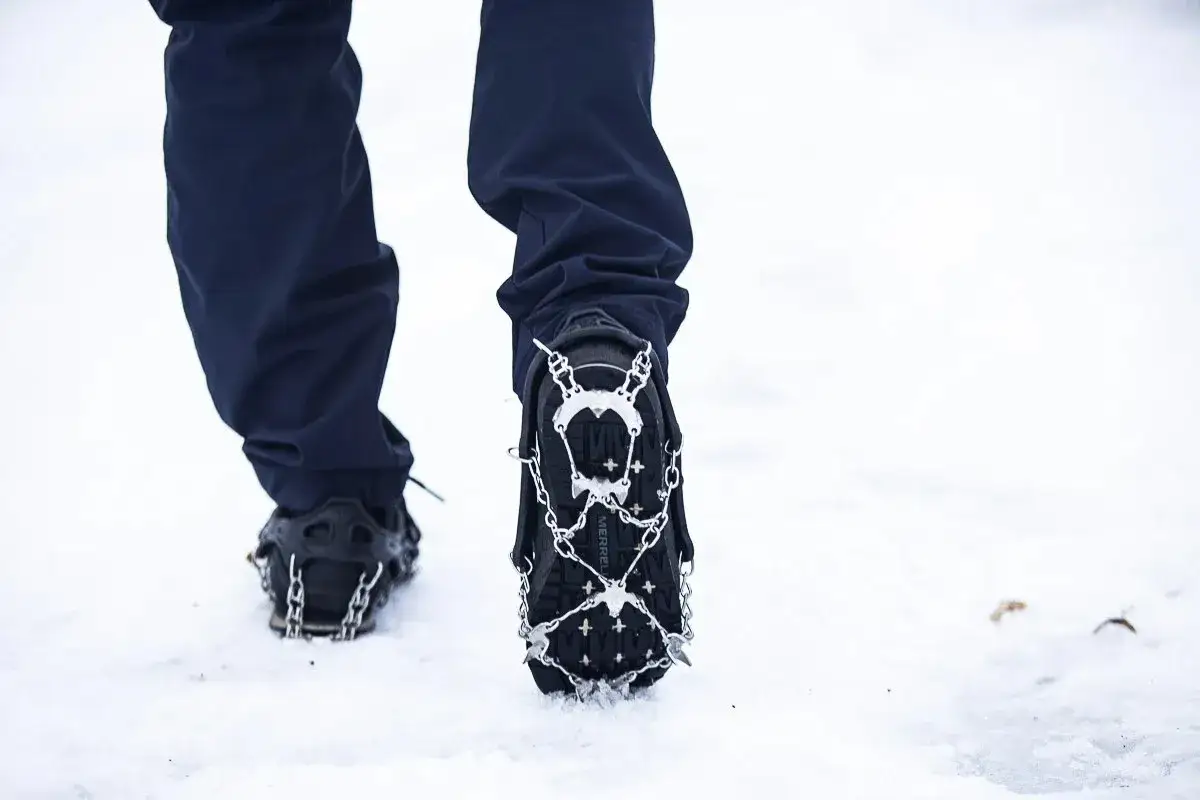 Nogi w butach z rakami, gotowe na wędrówkę w góry po śniegu.