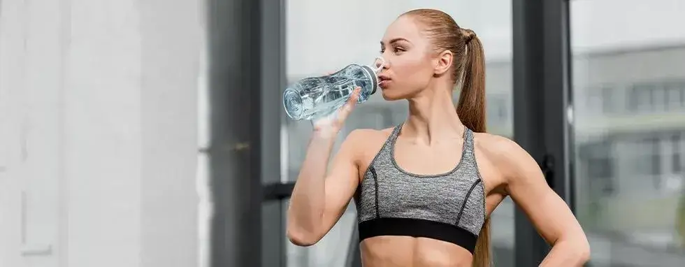 Sportowiec pije wodę przed treningiem