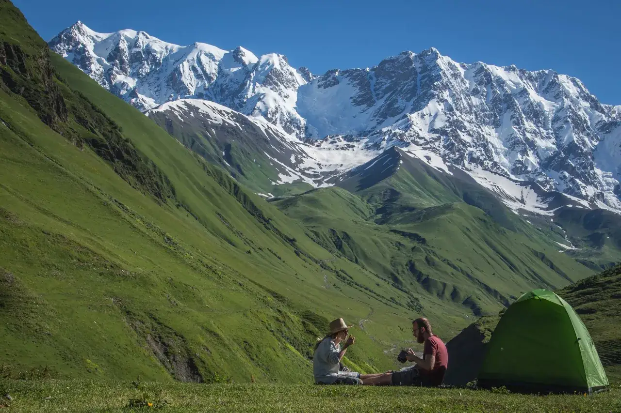 Para w namiocie na tle g&oacute;r. Ceny w Gruzji są przystępne, a widoki zapierają dech.