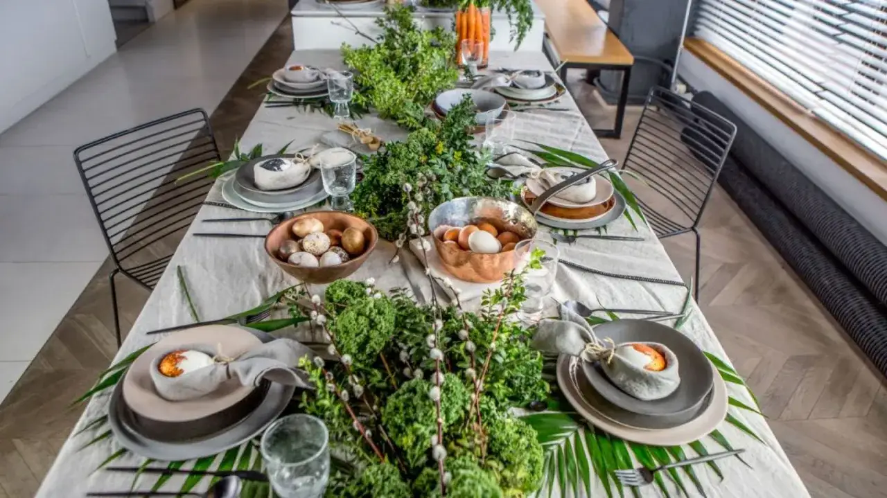Wielkanocny st&oacute;ł ozdobiony zielenią i pisankami. Idealne inspiracje, co na obiad wielkanocny.