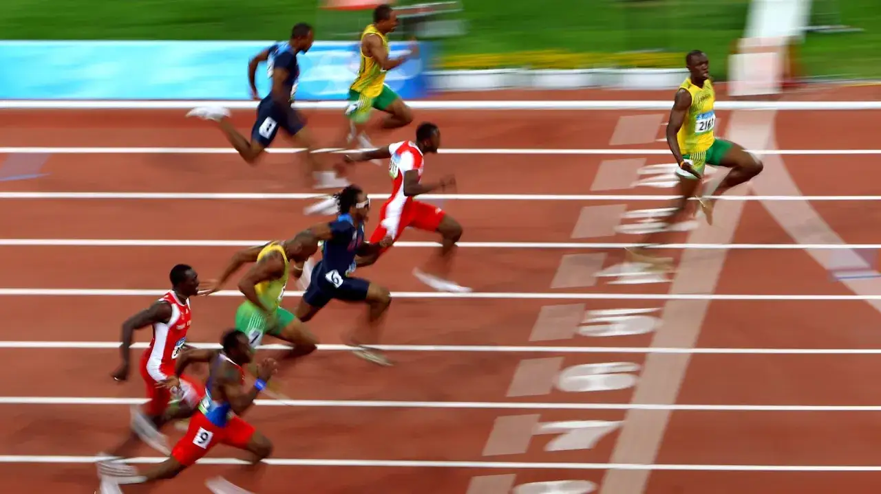 Usain Bolt w żółto-zielonym stroju biegnie po torze, ustanawiając nowy rekord. Inni sprinterzy walczą o zwycięstwo.