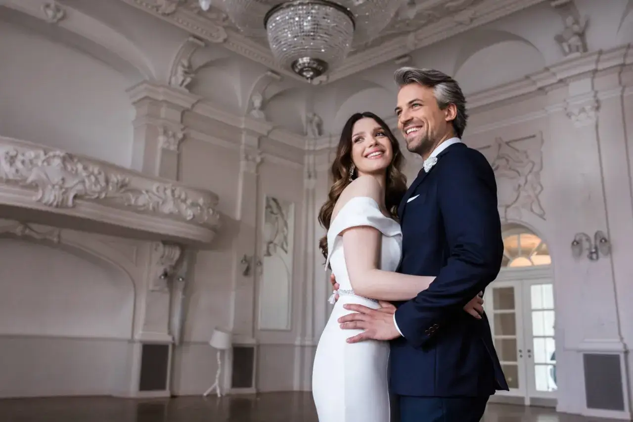 Elegancka panna młoda w białej sukni i pan młody w granatowym garniturze, idealnie dobrane stroje na ślub.