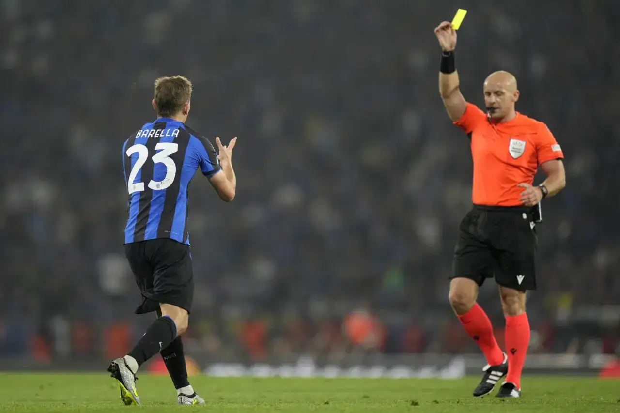 Sędzia pokazuje żółtą kartkę zawodnikowi z numerem 23. Czy to on pomoże swojej drużynie wygrać Ligę Mistrzów?