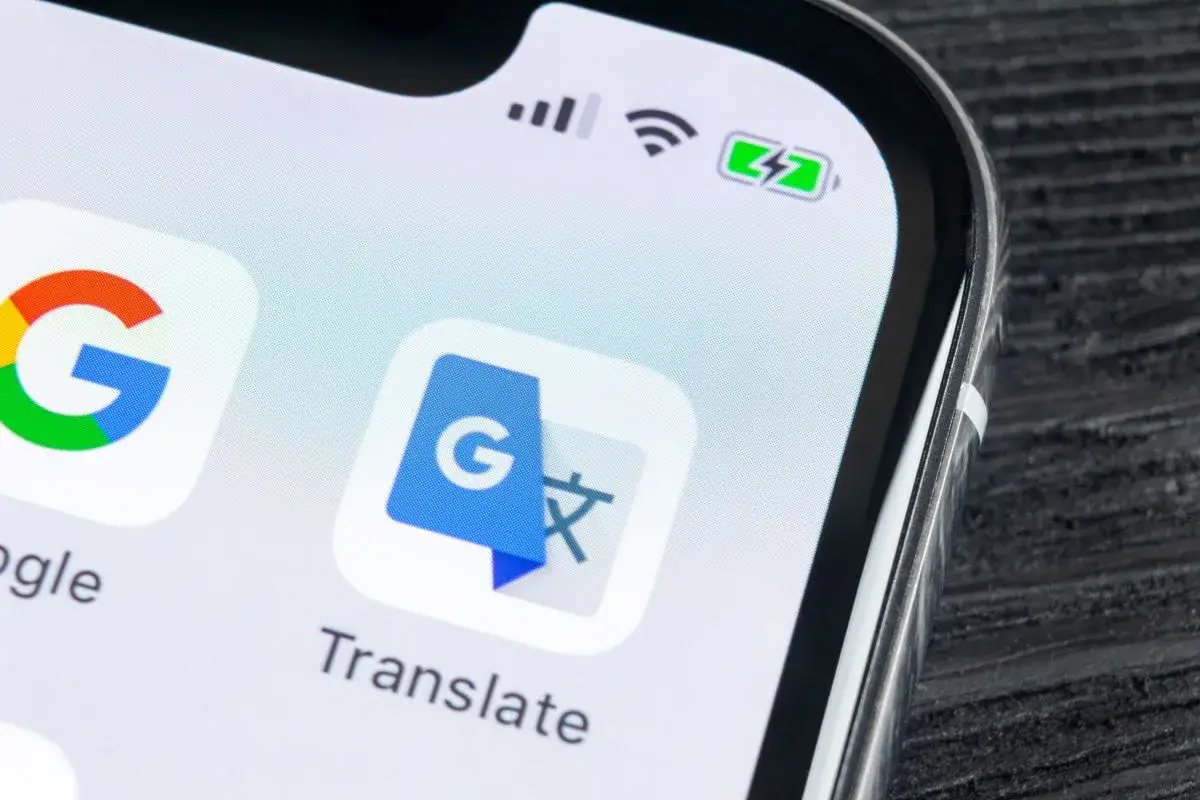 Ikona Google Translate na ekranie iPhone'a. Aplikacja Google Lens jest również widoczna obok.