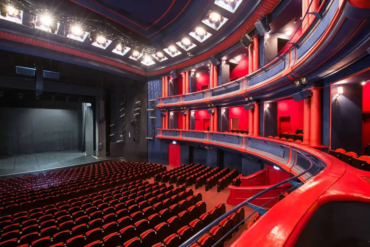 Wnętrze teatru z rzędami czerwonych foteli i balkonami. Trudno oszacować, ile miejsc ma Teatr Roma, ale jest ich mnóstwo!
