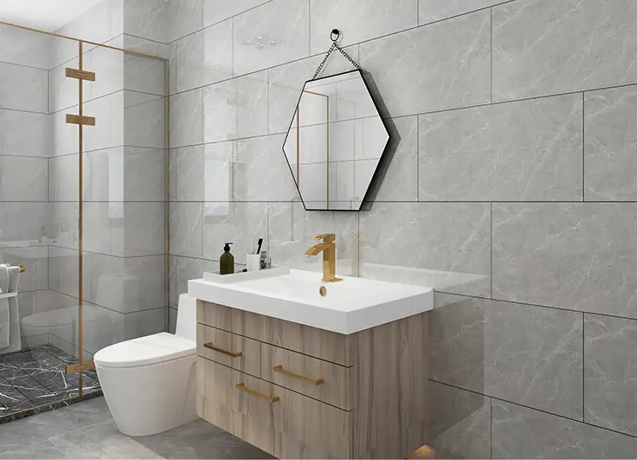Nowoczesna łazienka z szarymi, marmurkowymi panelami ściennymi, złotą armaturą i drewnianą szafką pod umywalkę.