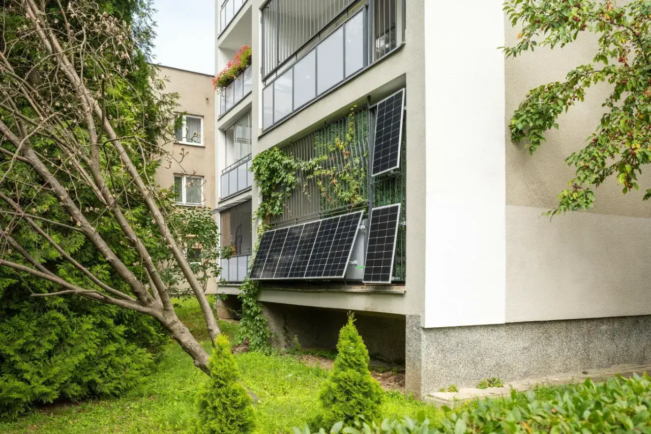 Nowoczesne panele fotowoltaiczne na balkonie, otoczone zielenią, tworzą ekologiczny zakątek.