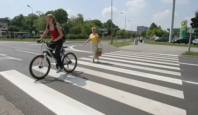 rowerzysta prowadzący rower przez przejście dla pieszych