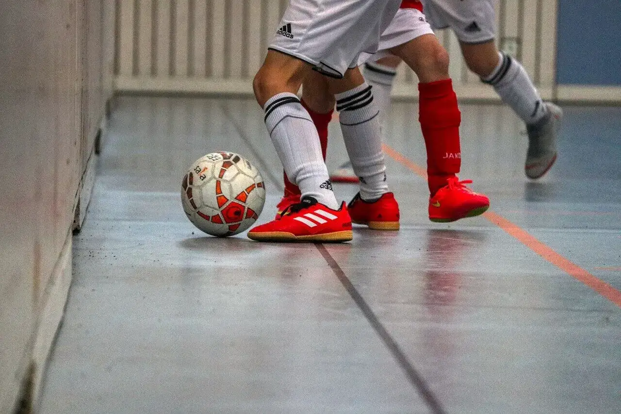 Piłkarze w czerwonych butach i białych getrach grają w halową piłkę nożną. To właśnie futsal &ndash; szybka i dynamiczna gra.