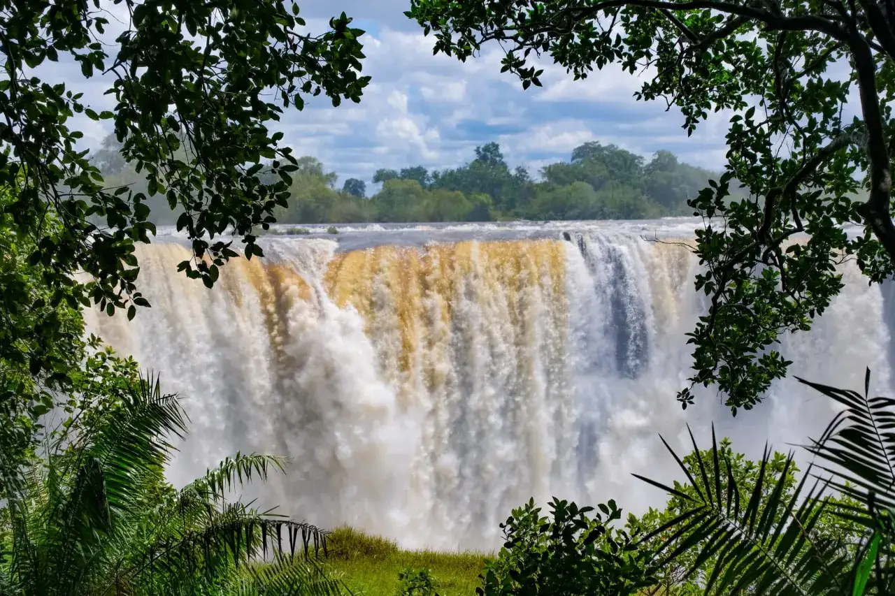 Potężny wodospad Wiktorii, jedna z głównych atrakcji Zimbabwe, widziany zza bujnej zieleni.