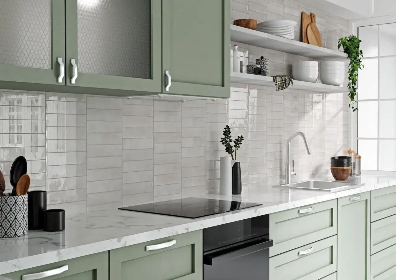 Jasne, oto propozycja:

Nowoczesna kuchnia z zielonymi szafkami i błyszczącymi, jasnymi płytkami między szafkami. Na blacie płyta indukcyjna i zlew.