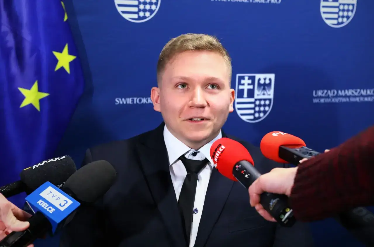 Młody mężczyzna w garniturze udziela wywiadu mediom. Jest rzecznikiem praw osób niepełnosprawnych, a jego słowa docierają do słuchaczy przez mikrofony TVP 3 Kielce i Radia Kielce.