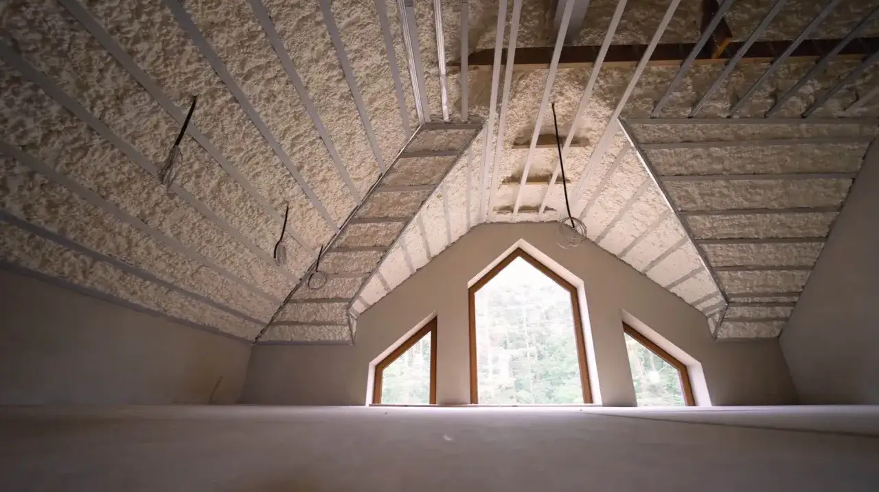 Poddasze z widocznym ocieplaniem pianką PUR. Metalowe profile konstrukcyjne i okablowanie tworzą ciekawy wzór na suficie.