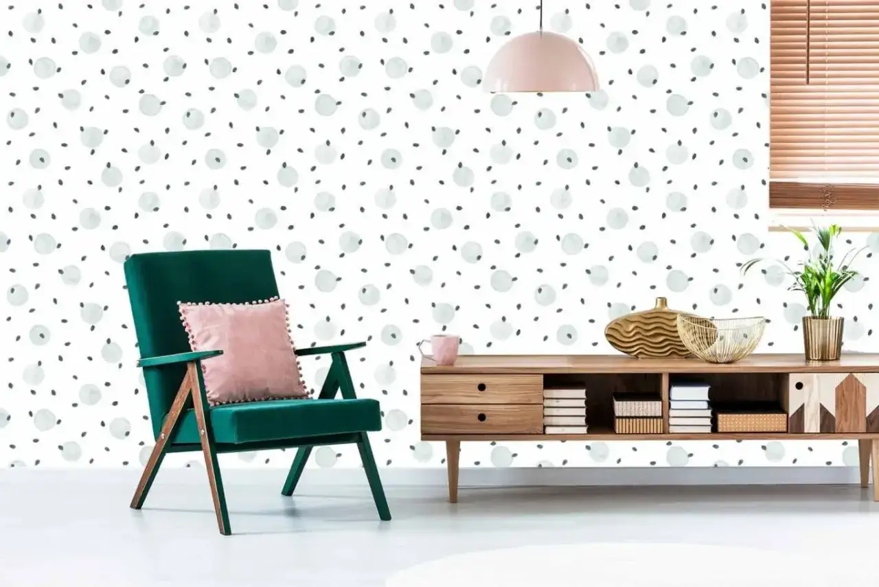 Zielone krzesło z różową poduszką na tle tapety w kropki. Czy można malować tapetę? Tak, jeśli jest odpowiednio przygotowana.