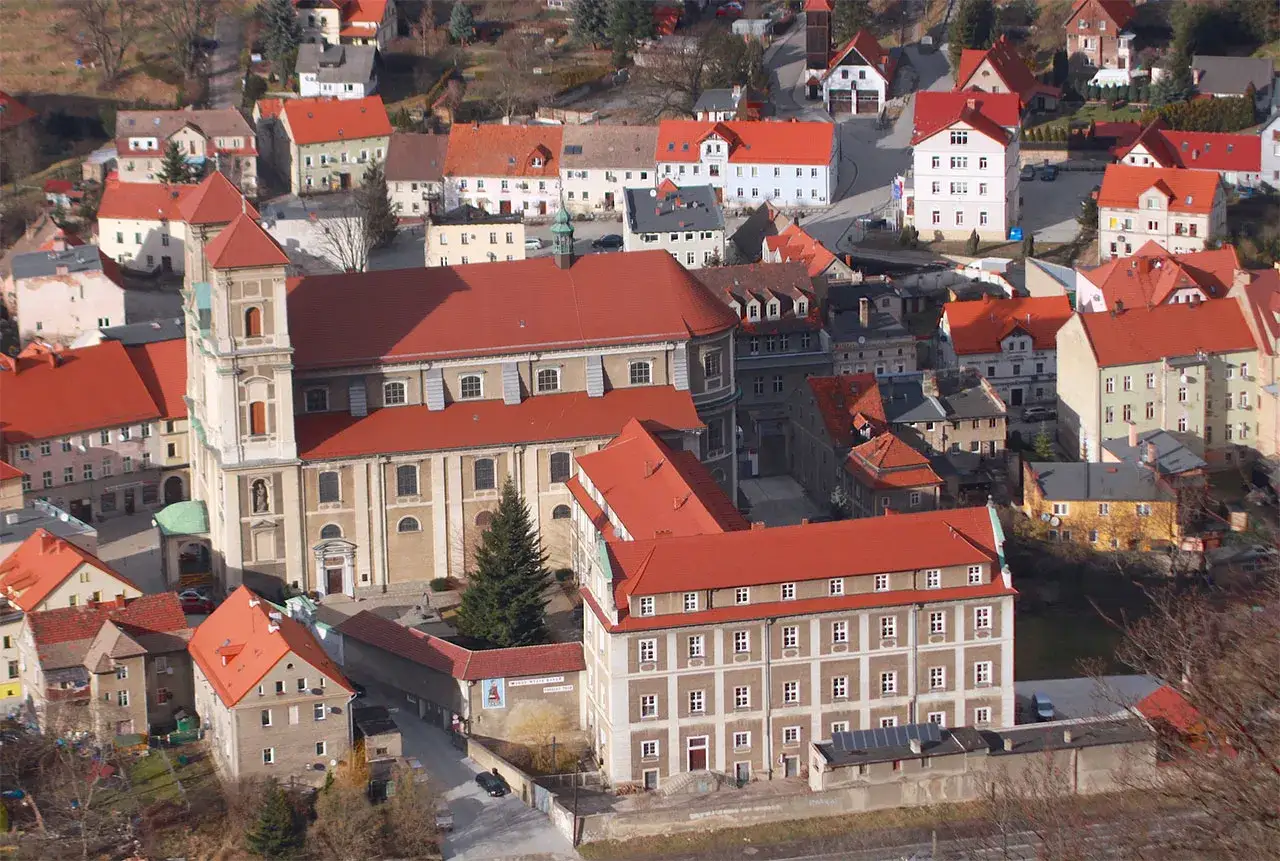 Widok z góry na miasteczko z czerwonymi dachami. W centrum imponująca bazylika, a obok niej inne budynki. Bardo atrakcje czekają!