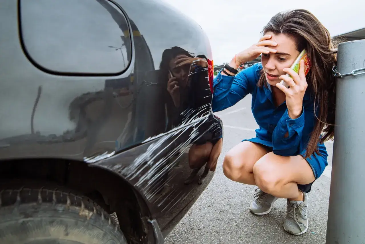 Kobieta w szoku po stłuczce. Jej auto w leasing ma poważne szkody z OC sprawcy. Dzwoni po pomoc.