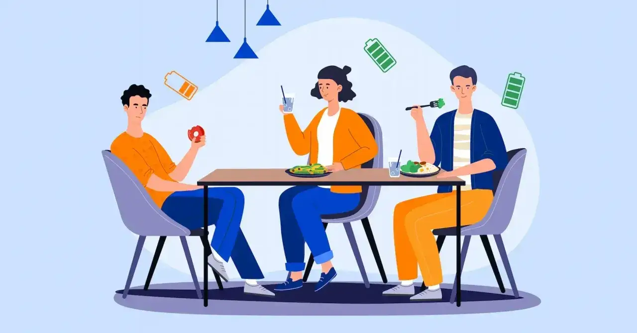 Ludzie jedzą przy stole, a nad nimi unoszą się ikony baterii. Szukasz najlepszych firm oferujących catering dla biur w dużych miastach w p...?