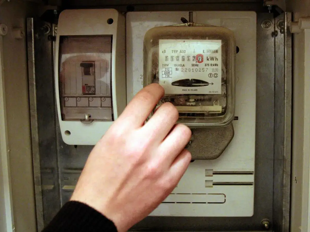 Dłoń wskazuje na licznik energii elektrycznej, budząc wątpliwości, czy licznik energii elektrycznej może oszukiwać.