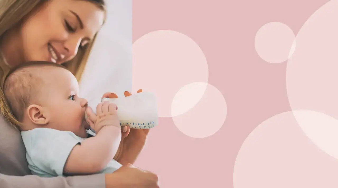 Uśmiechnięta mama karmi butelką swoje 3-miesięczne dziecko.