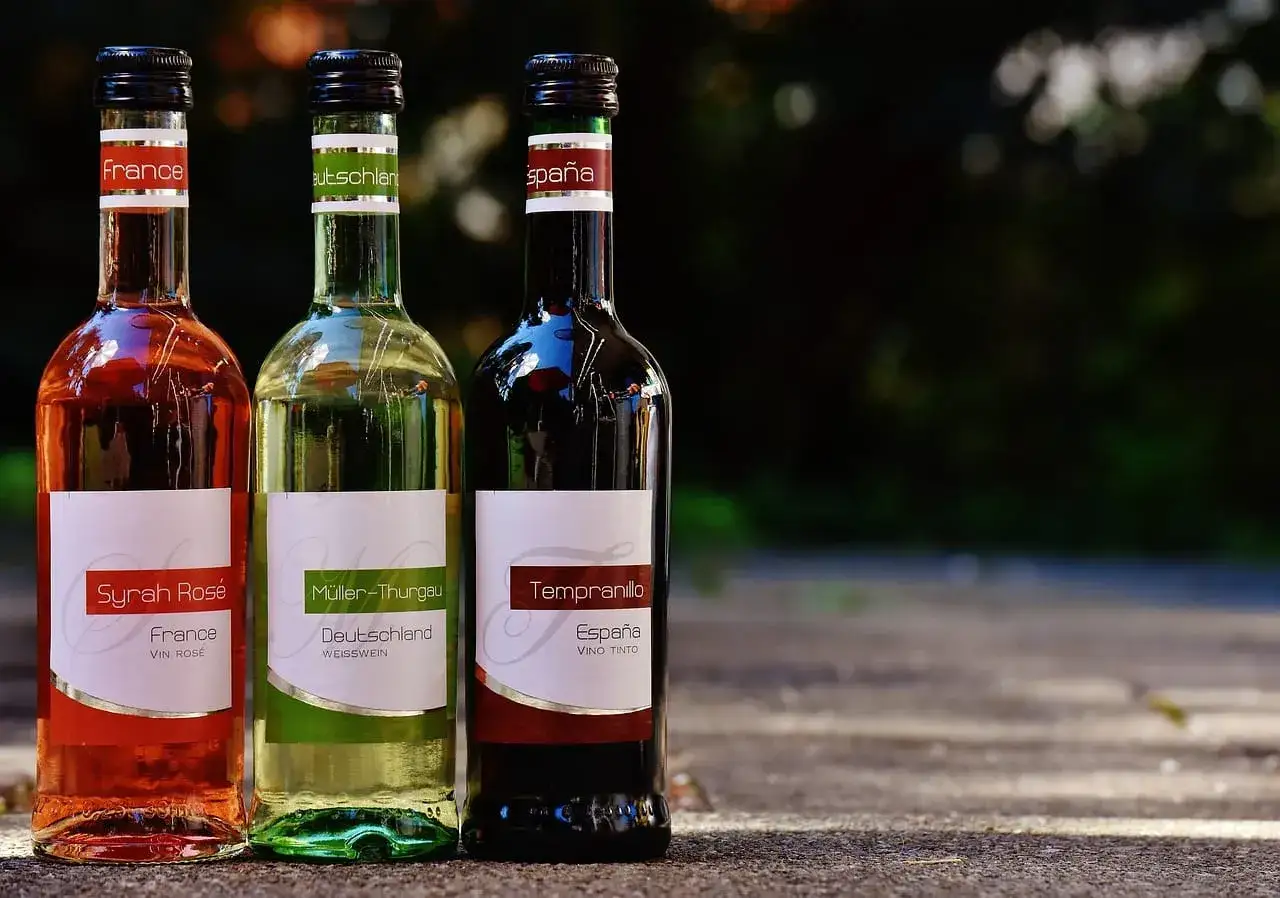 Trzy butelki wina: różowe z Francji, białe z Niemiec i czerwone z Hiszpanii. Na etykietach nie widać, ile wino ma procent.