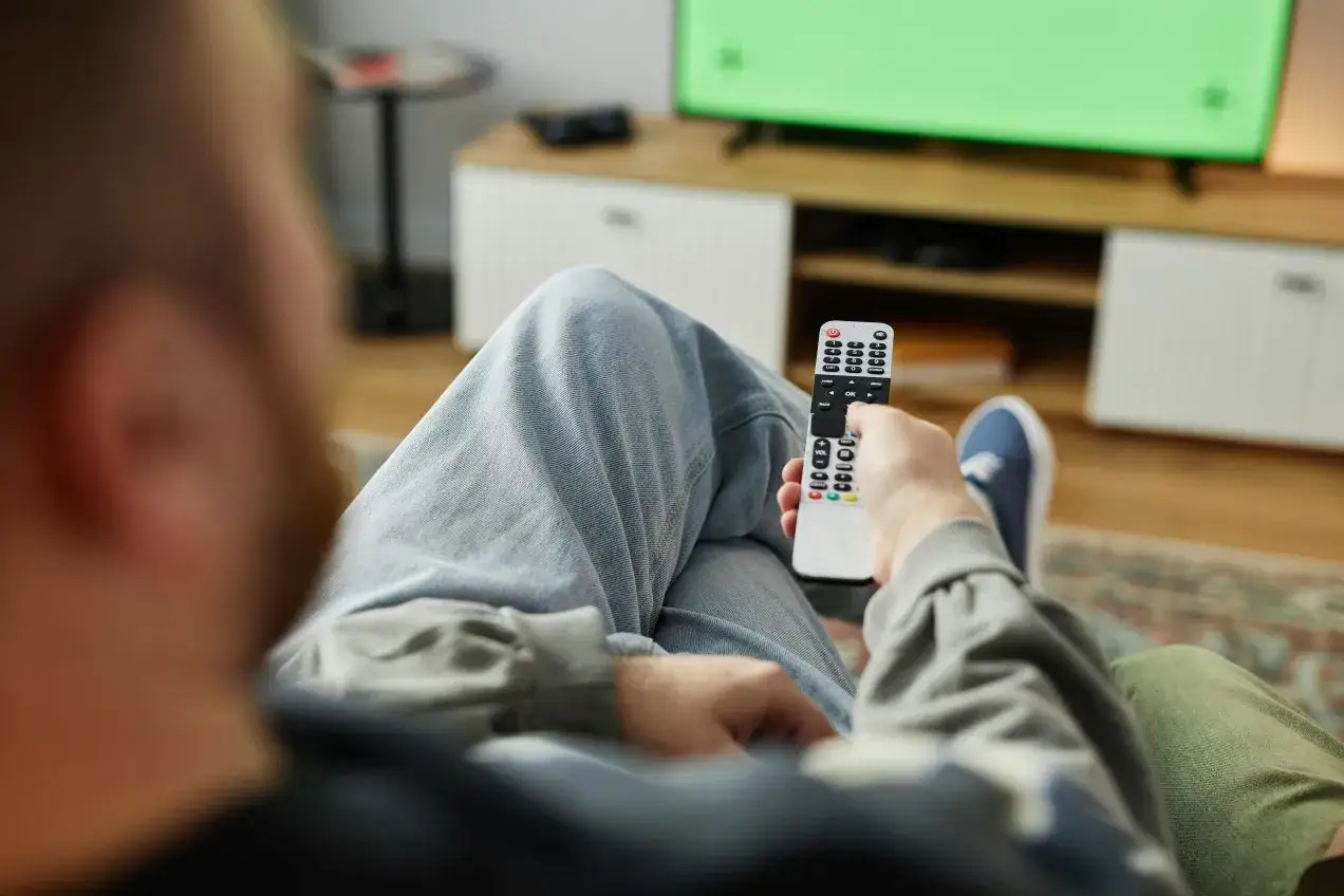 Mężczyzna z pilotem w ręku zastanawia się, czy trzeba płacić abonament żeby wygrać w RMF FM.