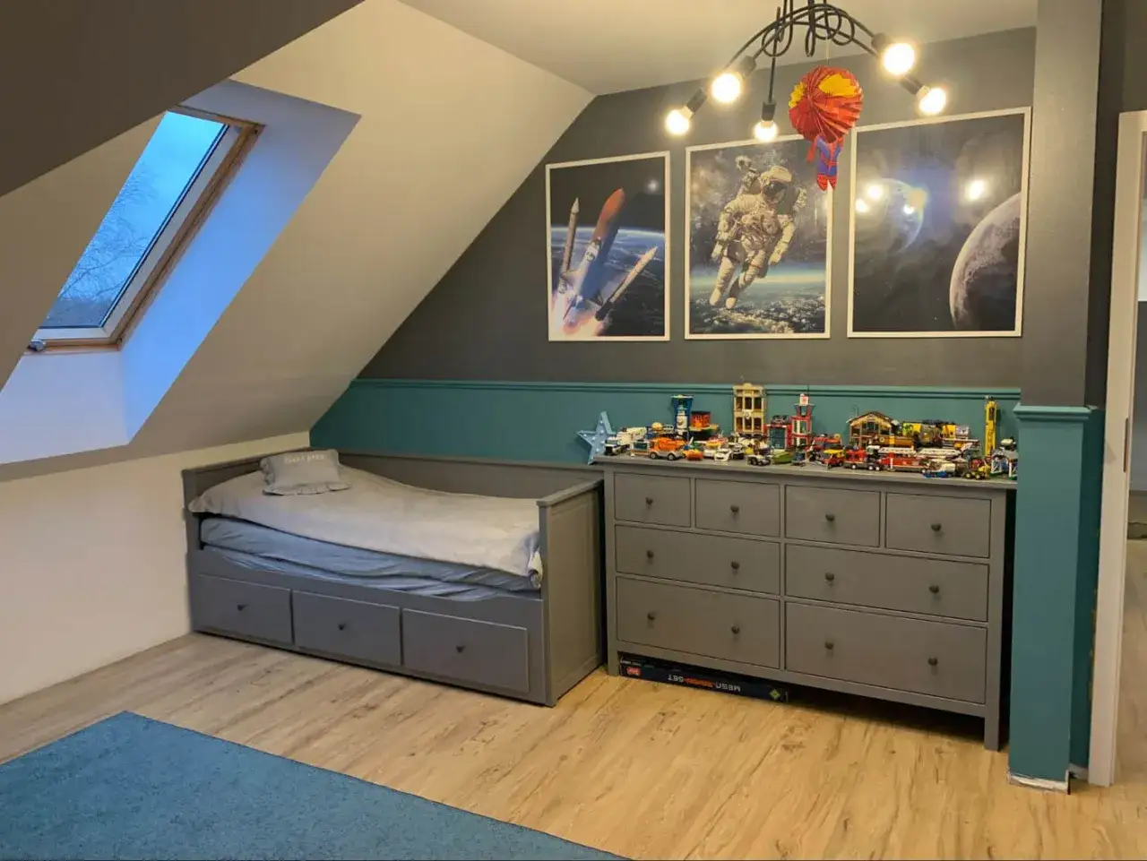 Pokój dla chłopca 10 lat inspiracje: kosmiczne motywy, łóżko z szufladami, komoda pełna klocków i plakaty z astronautą.