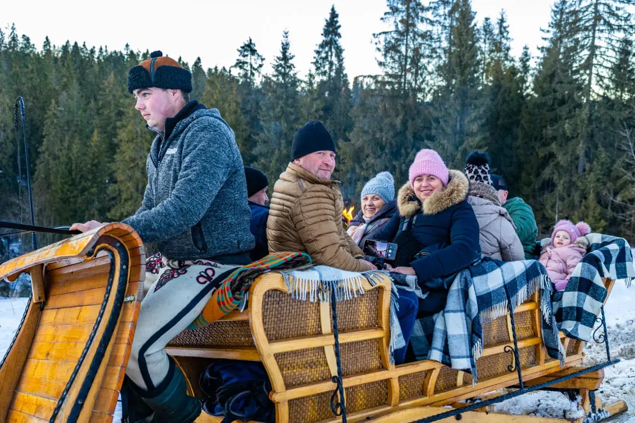 Rodzina cieszy się zimowym kuligiem w Bukowinie Tatrzańskiej. Wesoła gromadka w saniach, otulona kocami, przemierza ośnieżone tereny.
