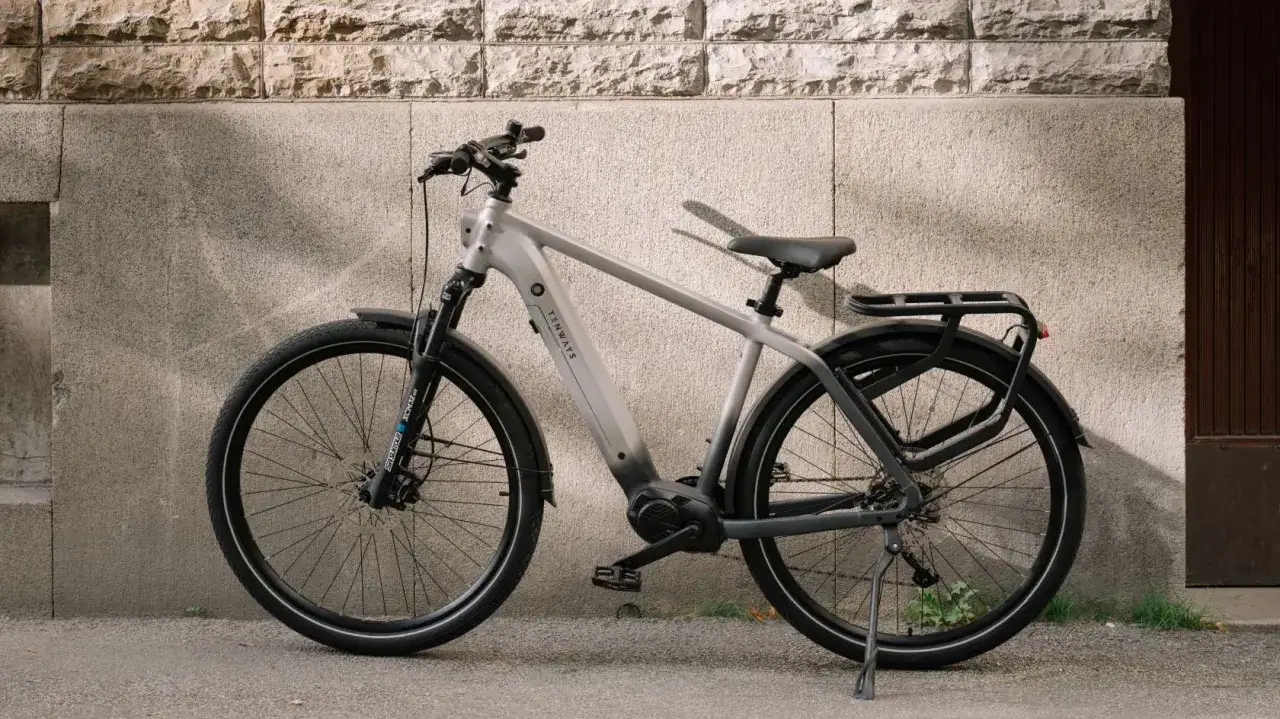 Szary rower elektryczny Tenways oparty o kamienną ścianę. Dowiedz się, jak myć rower elektryczny, by służył latami.