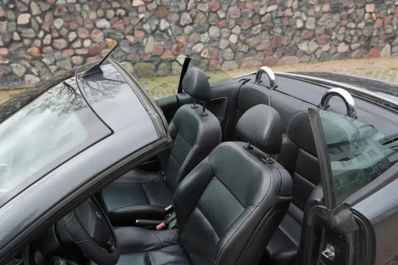 Wnętrze kabrioletu Peugeot 207 CC z czarną sk&oacute;rzaną tapicerką i chromowanymi pałąkami bezpieczeństwa.