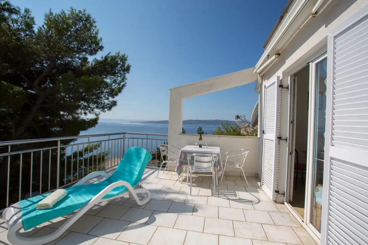 Tarasy z widokiem na morze, leżak i stolik z winem. Idealne miejsce, by sprawdzić apartament w Chorwacji.