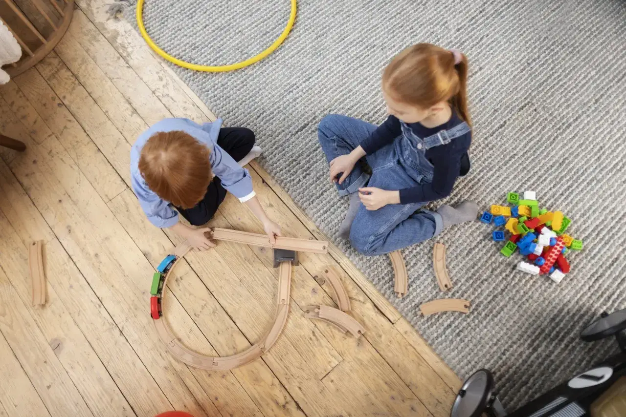 Dzieci bawią się pociągiem i klockami. Ich interakcja i zabawa wykluczają autyzm.