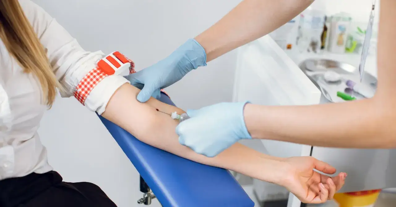 Pobieranie krwi do badań, np. kiedy najlepiej badać estradiol. Pielęgniarka w rękawiczkach pobiera krew pacjentce.