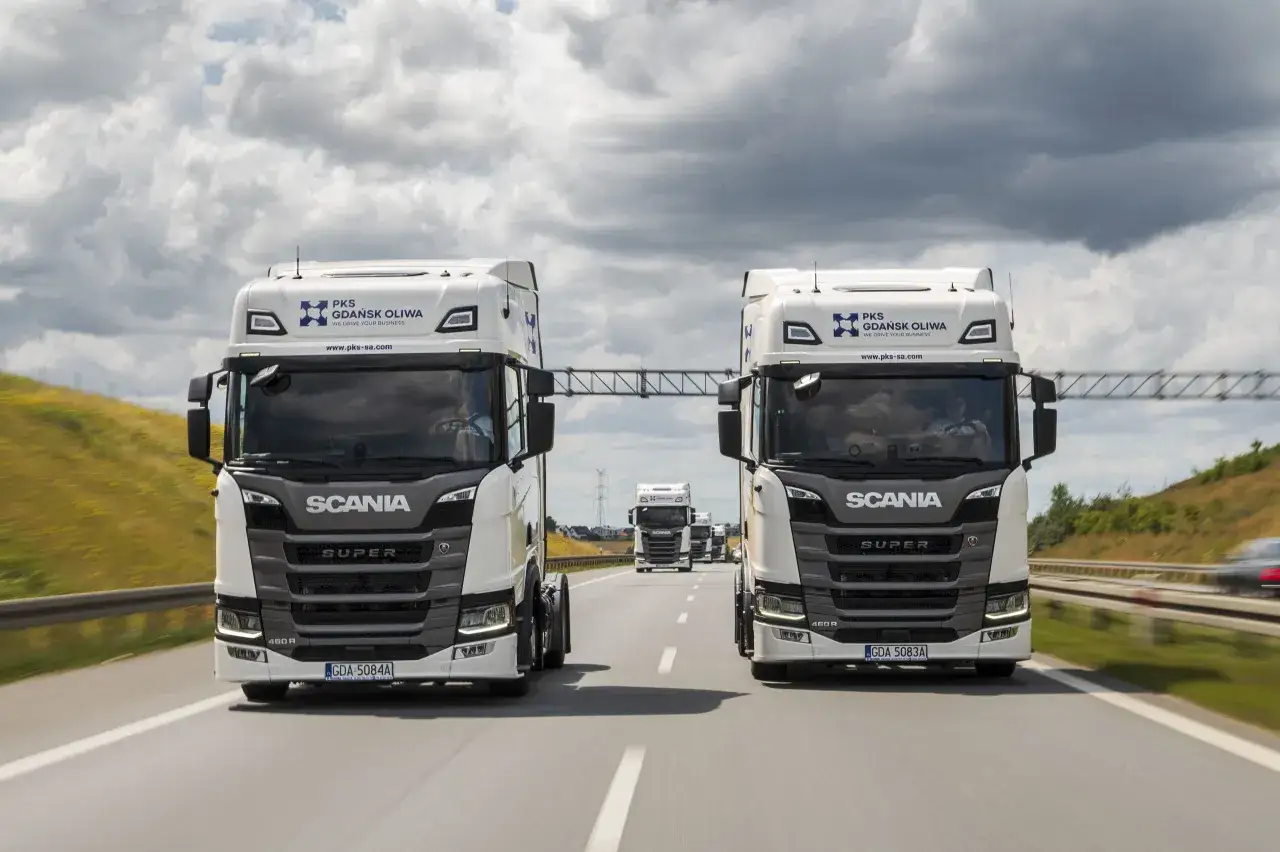 Dwa białe Scanie jadące autostradą. Spedycja transport krajowy to ich specjalność.