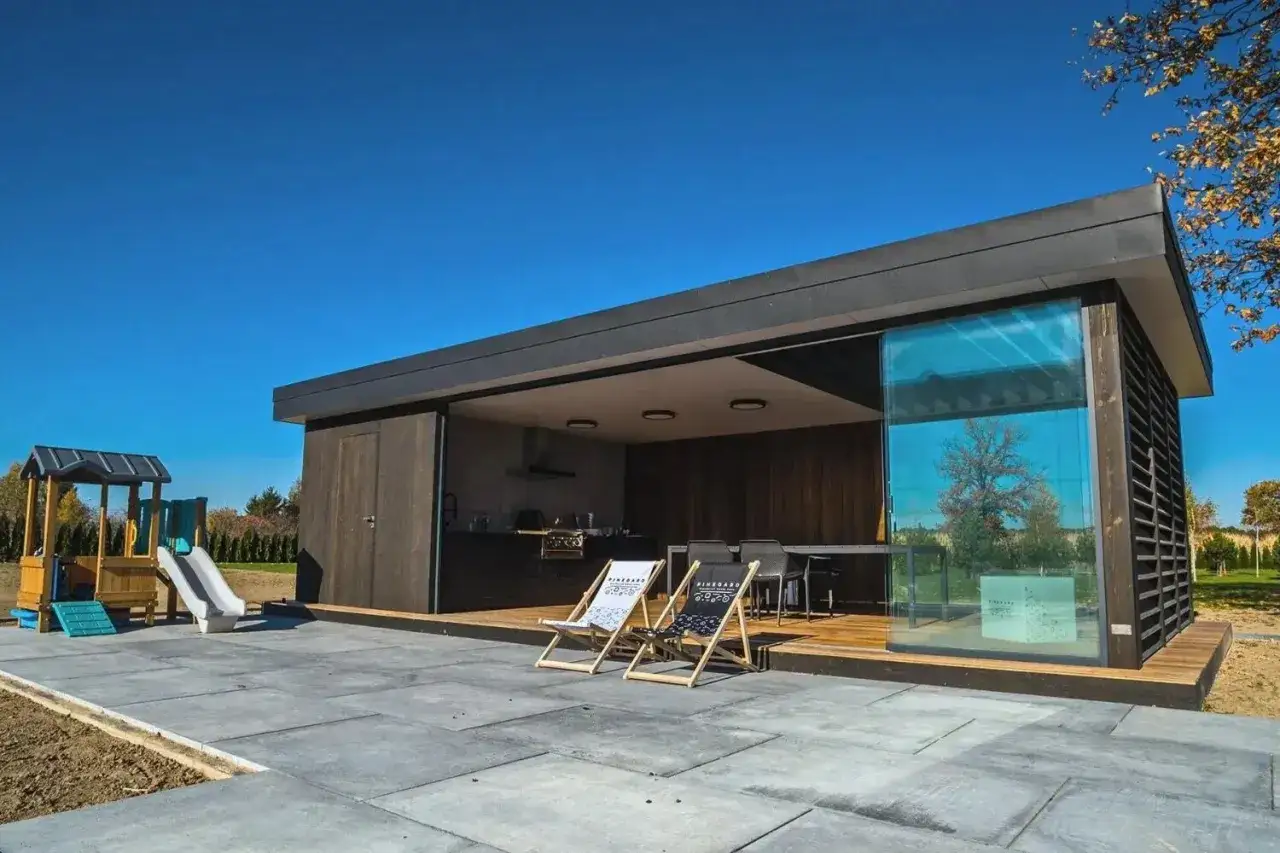 Nowoczesna altana z kuchnią i tarasem. Podłoga z płyt betonowych, idealna do wypoczynku.