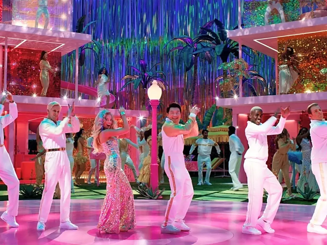 Scena z filmu tanecznego: Margot Robbie w błyszczącej sukni tańczy z innymi w r&oacute;żowej, bajkowej scenerii.