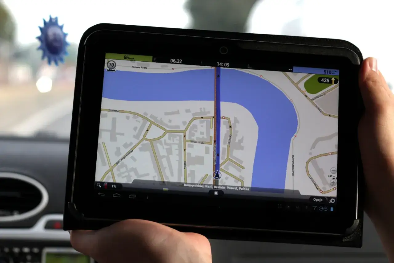 Dłoń trzyma tablet z mapą nawigacyjną, pokazującą trasę w Krakowie. To może być pomocne, jak zaktualizować Automapę, by zawsze mieć najnowsze drogi.
