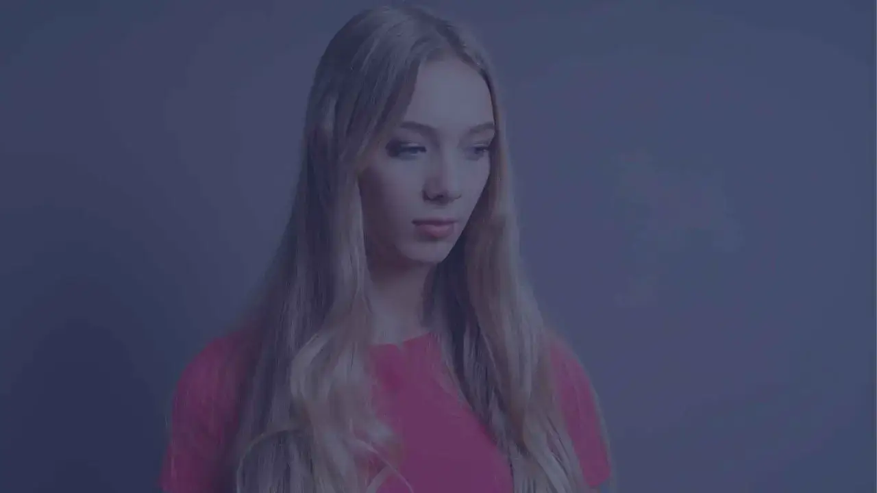 Młoda kobieta o blond włosach, w różowej bluzce, zamyślona. Czy to obraz tego, co to znaczy INFJ?