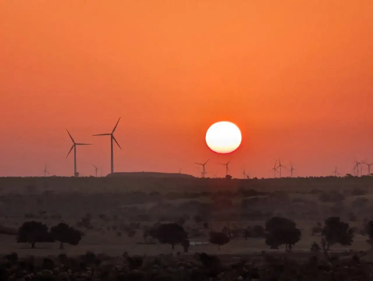 Turbiny wiatrowe na tle zachodzącego słońca
