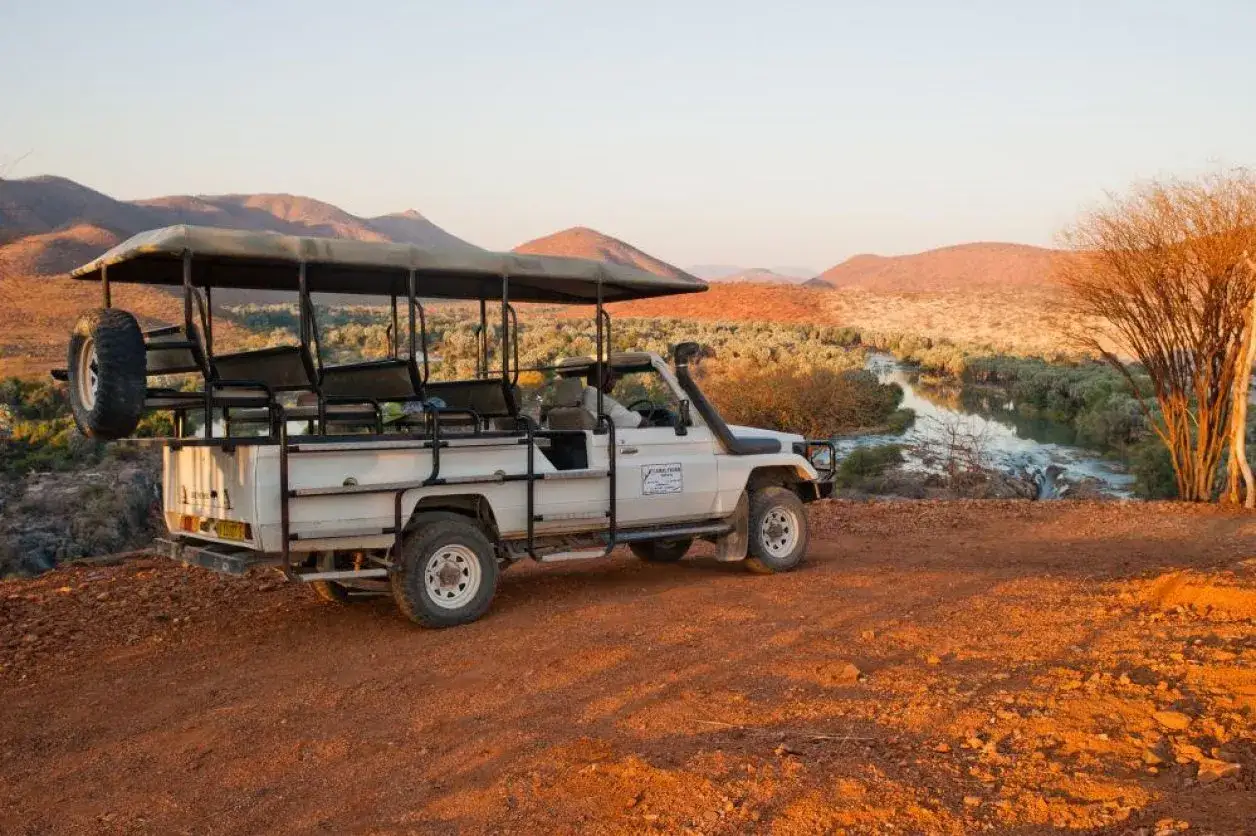 Safari jeep na tle pustynnego krajobrazu Namibii. Sprawdź atrakcyjne ceny wycieczek!