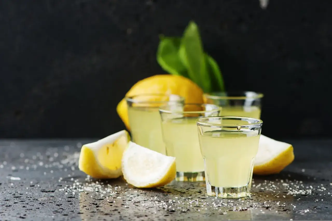 Kieliszki z orzeźwiającym limoncello, cytryny i cukier. Idealny sposób, by dowiedzieć się, jak pić limoncello.