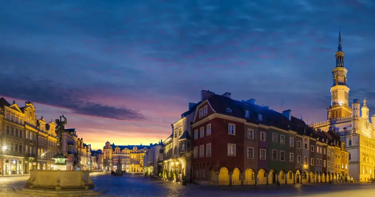 Poznański Rynek o zmierzchu, idealne miejsce na jednodniowe wycieczki z Poznania. Kolorowe kamieniczki i ratusz oświetlone zachodzącym słońcem.