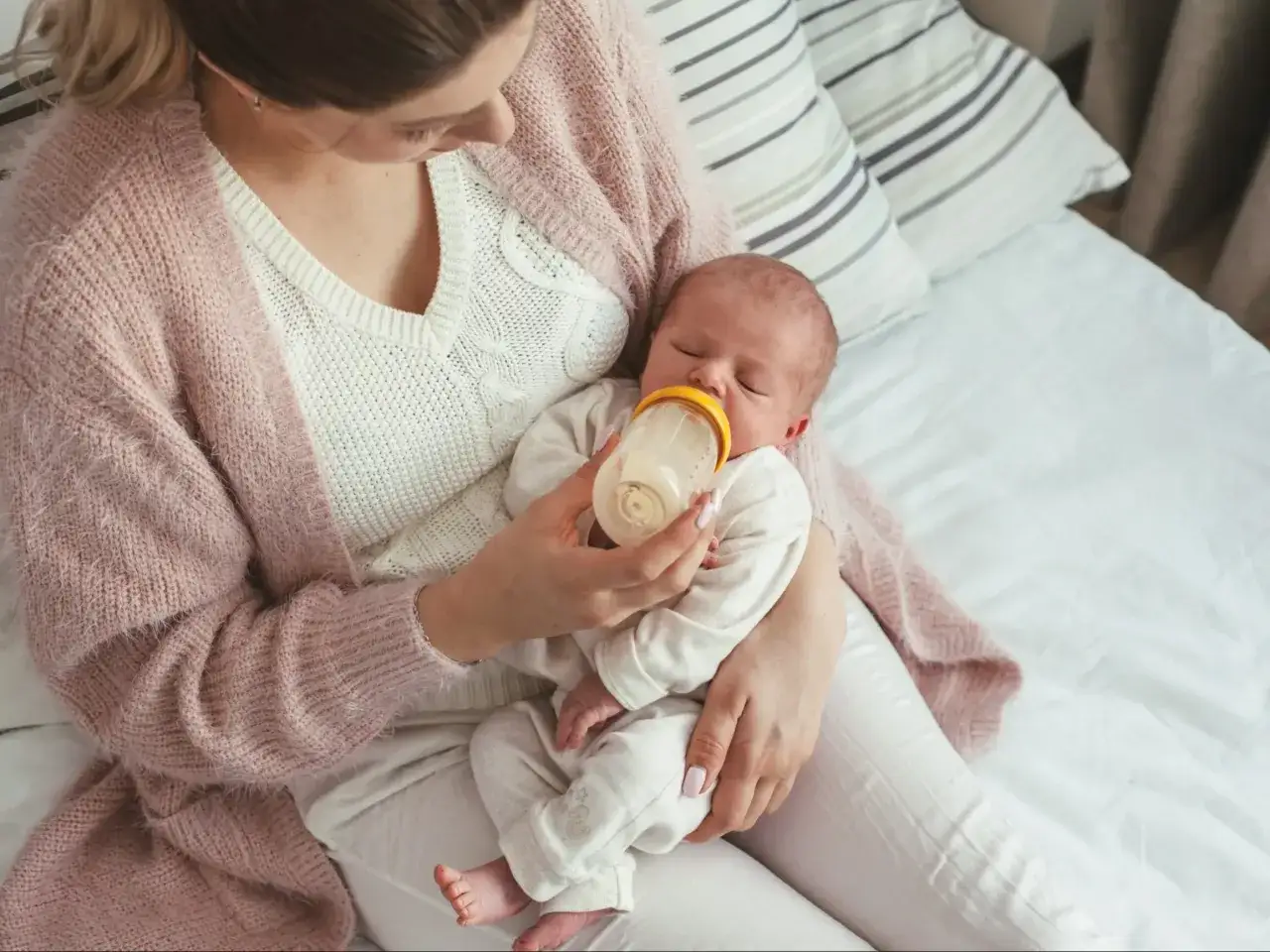 Mama karmi butelką śpiące niemowlę. Warto wiedzieć, co ile karmic 4 miesieczne niemowle, by zapewnić mu odpowiedni rozwój.