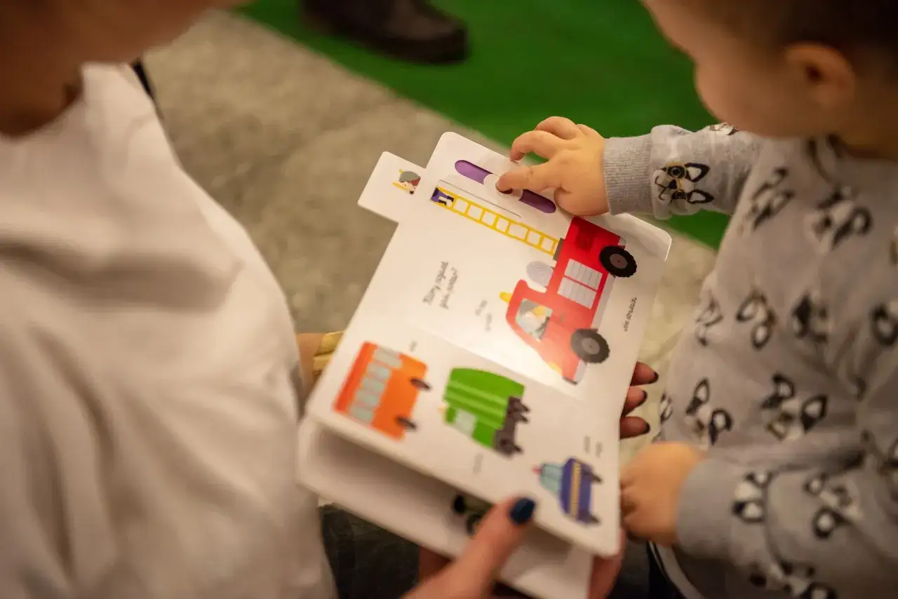 Dziecko bawi się książkami interaktywnymi dla dzieci, przesuwając element z drabiną w wozie strażackim.