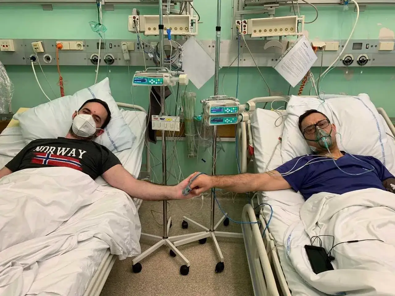 Dw&oacute;ch mężczyzn w szpitalnych ł&oacute;żkach, wspierających się nawzajem podczas rekonwalescencji po usunięciu nerki. Trzymają się za ręce, pokazując siłę więzi.