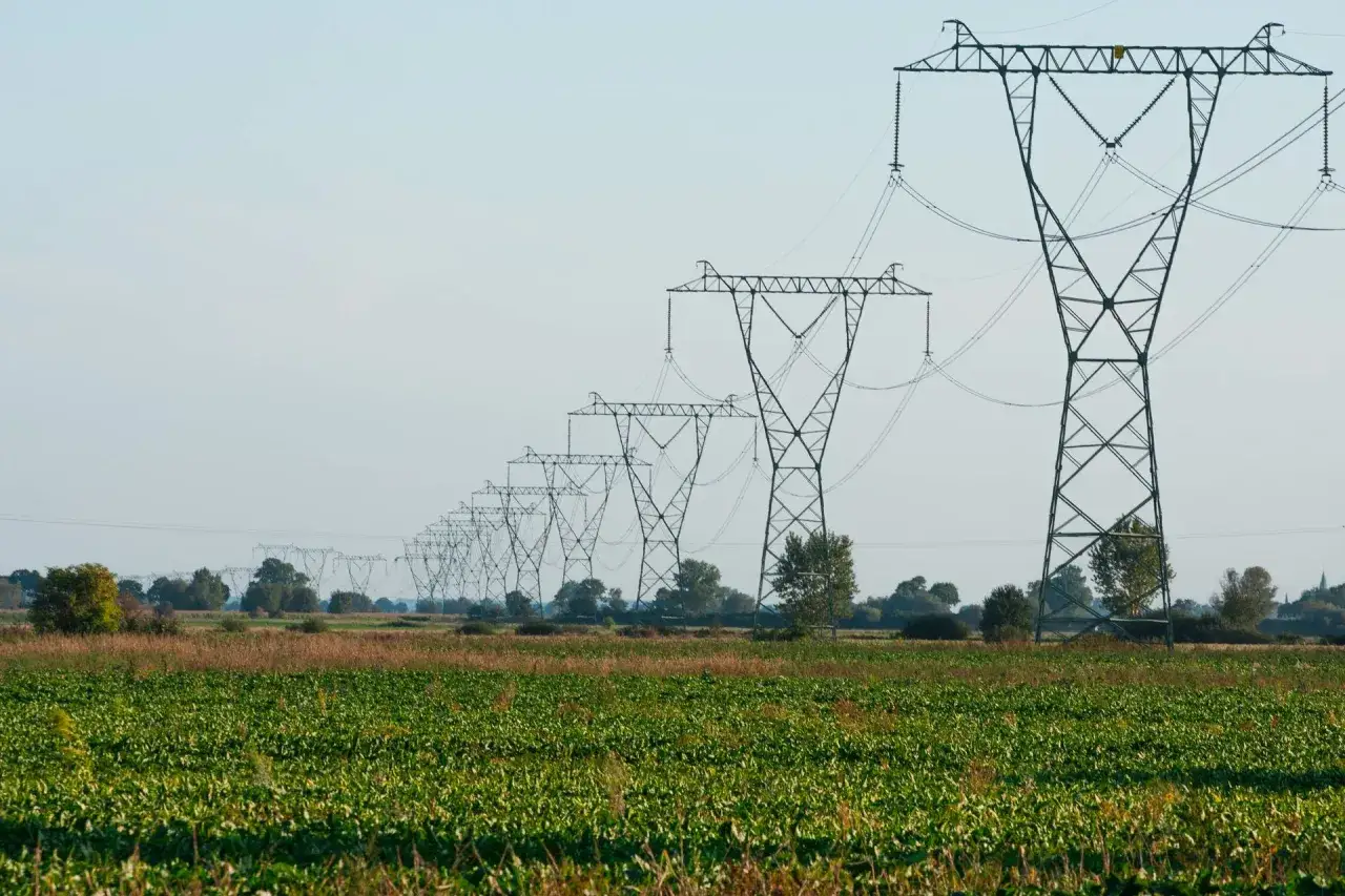 Linia energetyczna 110 kV biegnie przez pole uprawne. Zachowanie bezpiecznej odległości od linii wysokiego napięcia jest kluczowe.