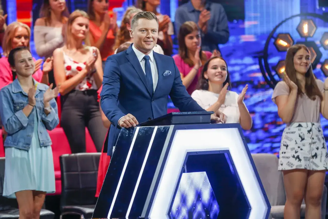 Uczestnicy klaszczą, gdy prowadzący stoi przy podium. Czy nagroda w finale Jaka to melodia jest wypłacana w gotówce czy na konto?