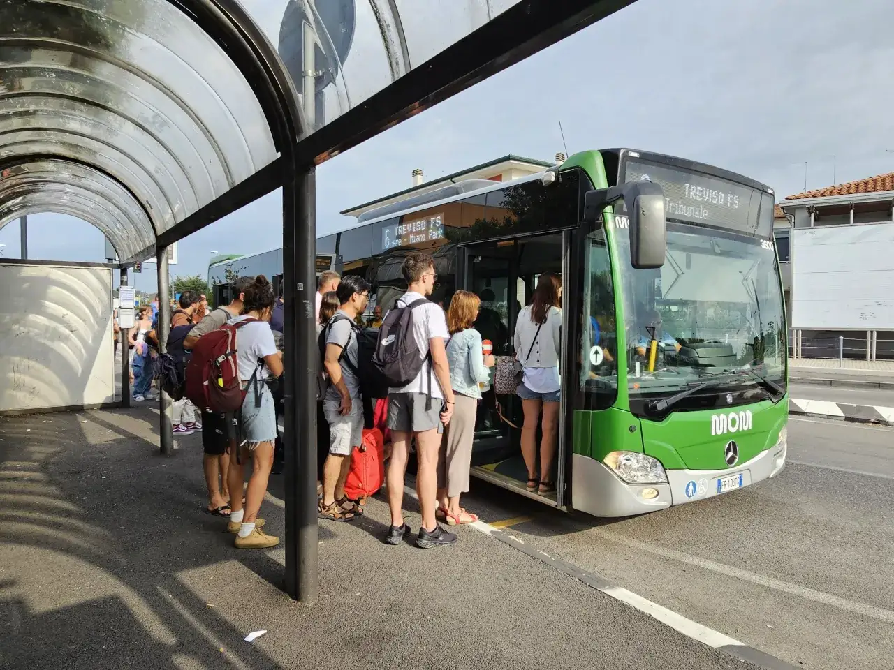 Ludzie czekają na zielony autobus linii 6 do Treviso FS przy przystanku, który obsługuje port lotniczy Treviso.