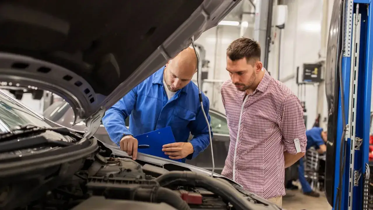 Mechanik pokazuje klientowi dokumentację odbioru samochodu po naprawie bezgotówkowej.