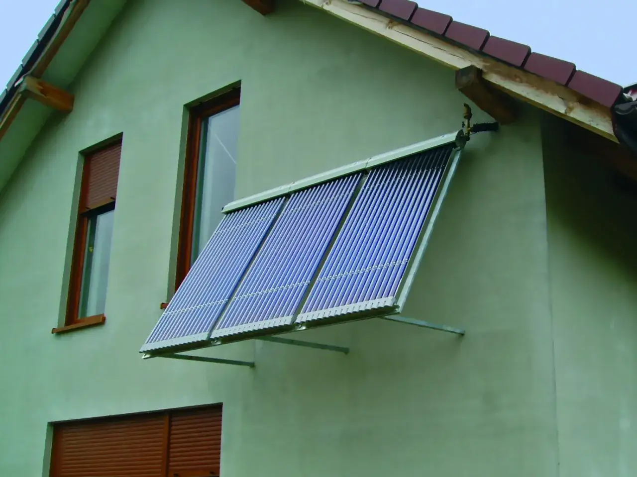 Dofinansowanie do kolektor&oacute;w słonecznych: zamontowane na ścianie domu trzy rzędy kolektor&oacute;w rurowych, wykorzystujących energię słoneczną do ogrzewania.