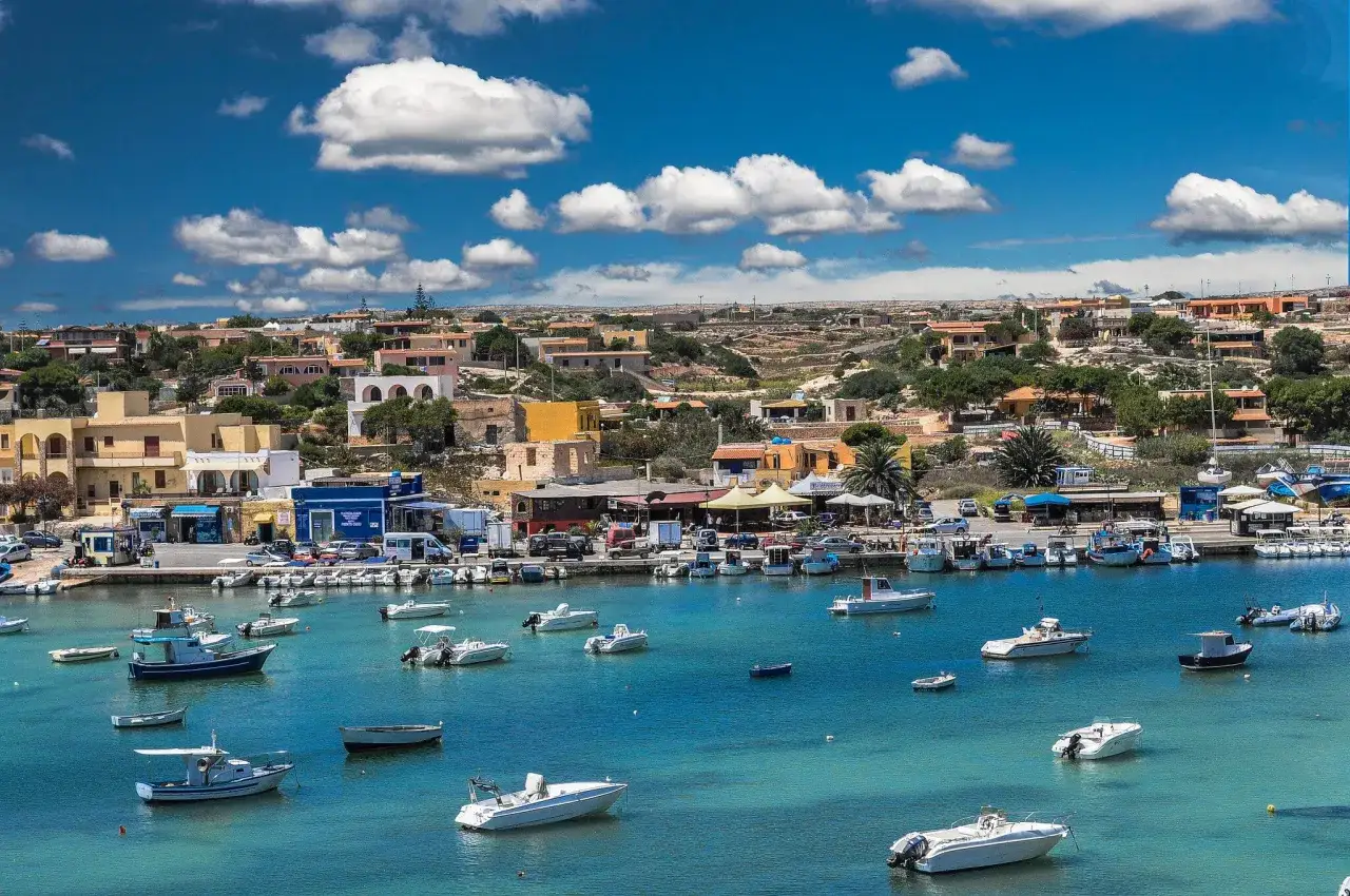 Port na Lampedusie, gdzie cumują liczne łodzie. Marzysz o podróży? Sprawdź, lampedusa jak się dostać!